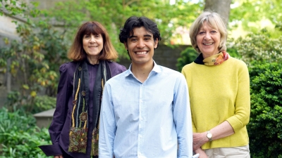 Student standing between two faculty members outside